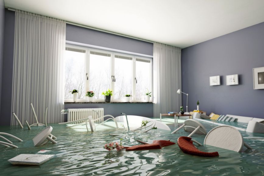 Salón de vivienda inundado por lluvias torrenciales, muebles flotando tras una DANA